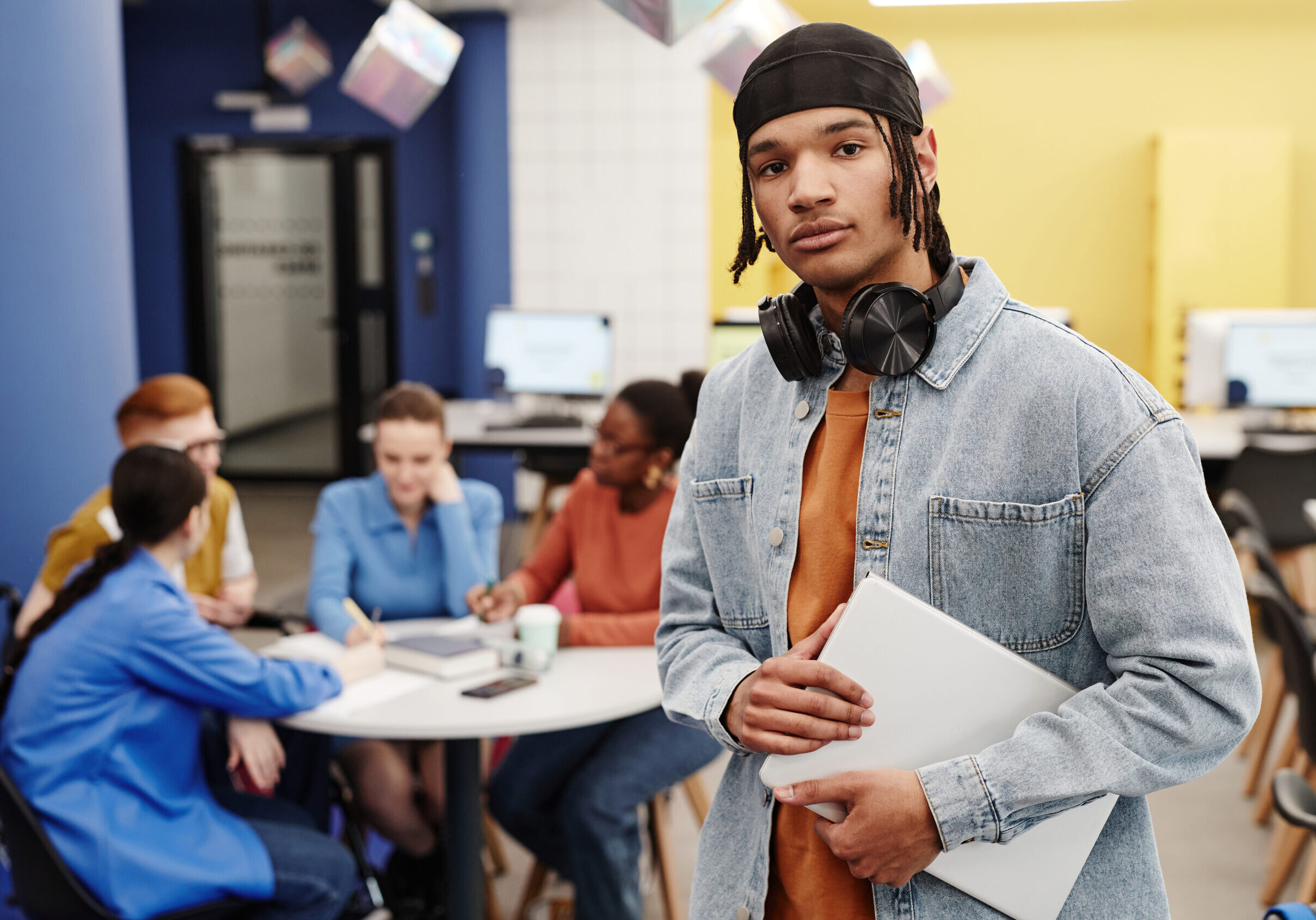 Vibrant waist up portrait of young black man in college library looking at camera, copy space